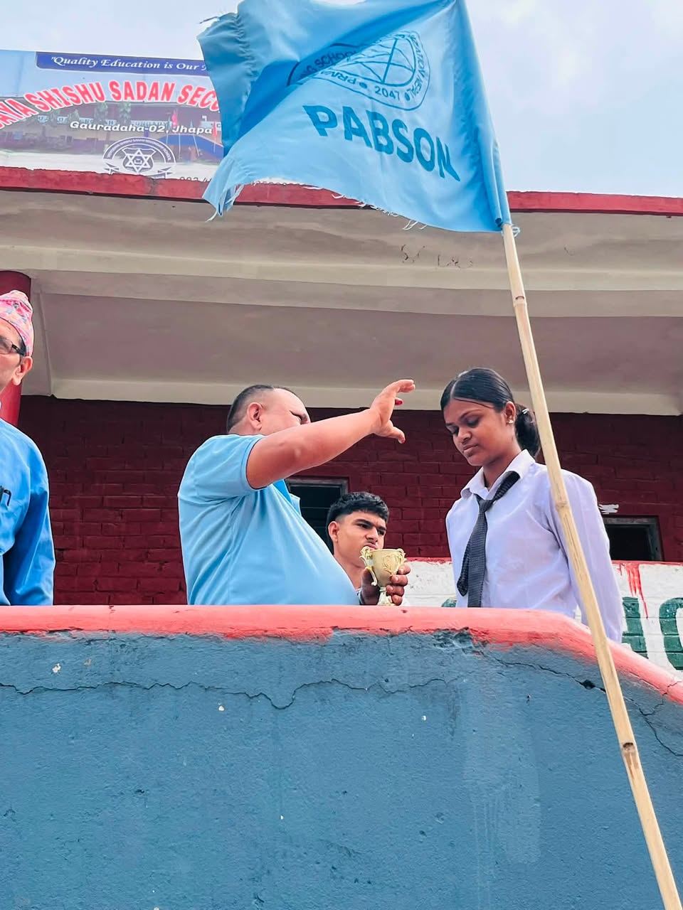 Student receiving trophy in PABSON competition on school stage
